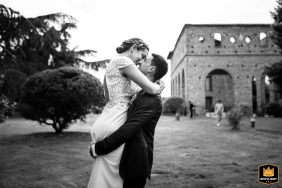 At the Domaine du Beyssac in Haute-Garonne, the loving groom expresses his affection by lifting the bride high up for a romantic kiss on the venue's lush grassy lawn.